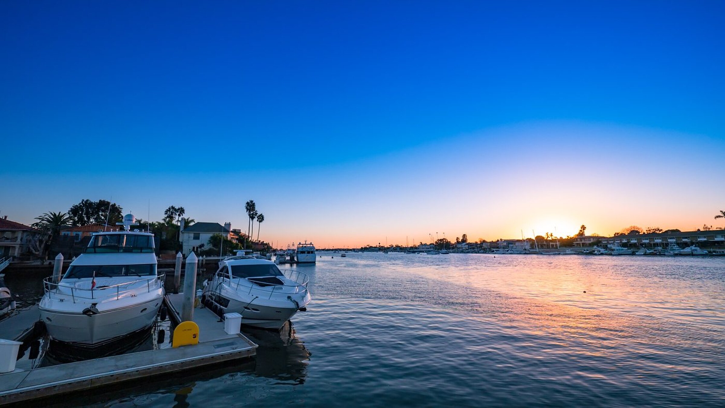 A sailboat on calm California harbor water at golden hour